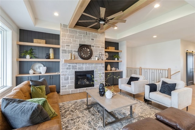 living room featuring a fireplace, light wood-type flooring, and a tray ceiling