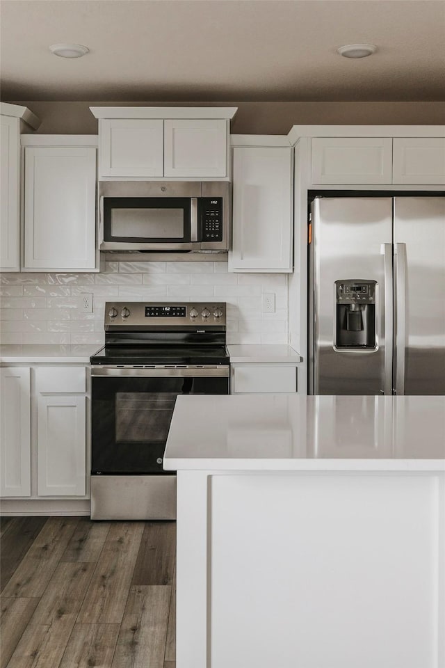 kitchen featuring backsplash, appliances with stainless steel finishes, dark hardwood / wood-style floors, and white cabinets