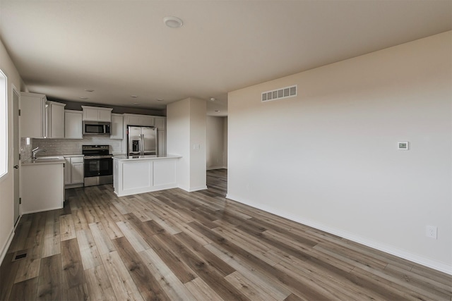 kitchen featuring sink, white cabinetry, light wood-type flooring, appliances with stainless steel finishes, and decorative backsplash