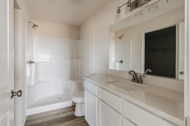 bathroom with walk in shower, vanity, toilet, and hardwood / wood-style flooring