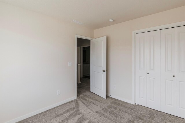 unfurnished bedroom featuring light colored carpet and a closet