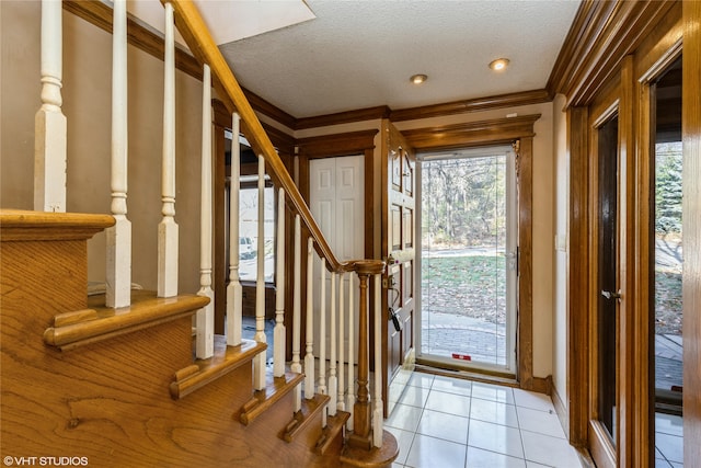 tiled foyer entrance with a textured ceiling, crown molding, and a healthy amount of sunlight