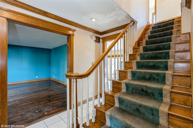 stairway with hardwood / wood-style floors, a textured ceiling, and crown molding