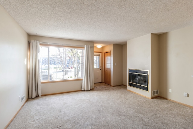 unfurnished living room featuring light colored carpet and a textured ceiling