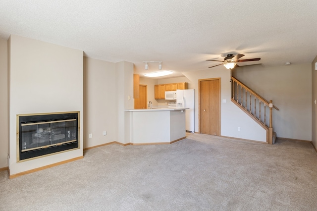 unfurnished living room featuring light carpet, a textured ceiling, and ceiling fan