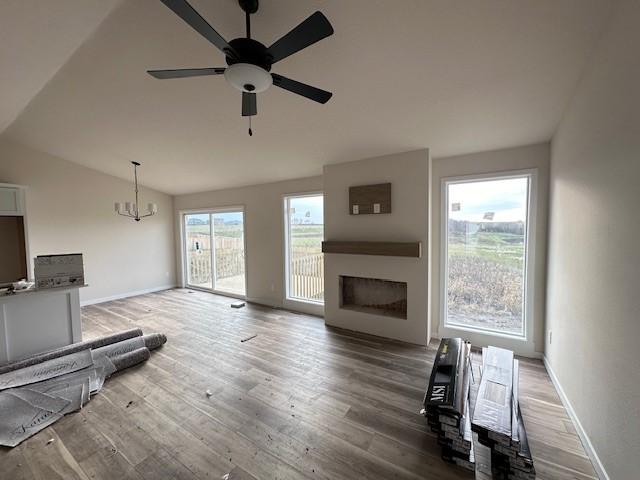 living room featuring wood-type flooring, ceiling fan with notable chandelier, and lofted ceiling