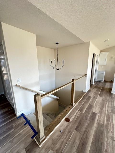 staircase featuring a chandelier, a textured ceiling, and hardwood / wood-style flooring