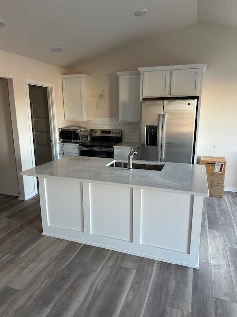 kitchen with white cabinetry, sink, appliances with stainless steel finishes, and vaulted ceiling