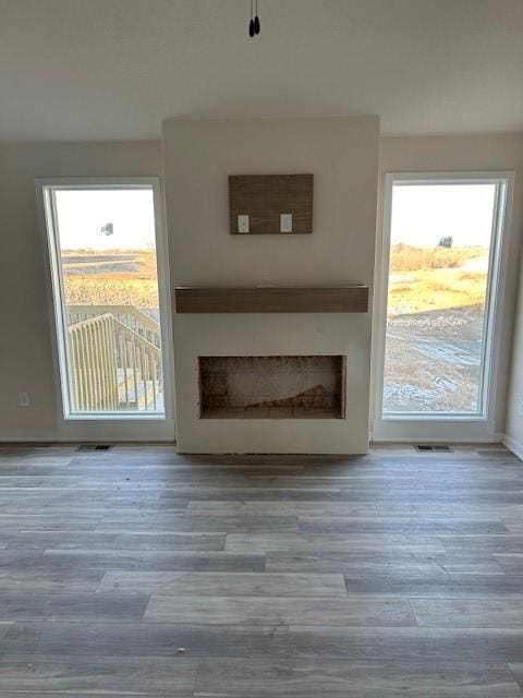 unfurnished living room featuring a wealth of natural light, a fireplace, and hardwood / wood-style flooring