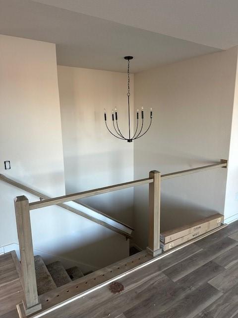 stairway with wood-type flooring and an inviting chandelier