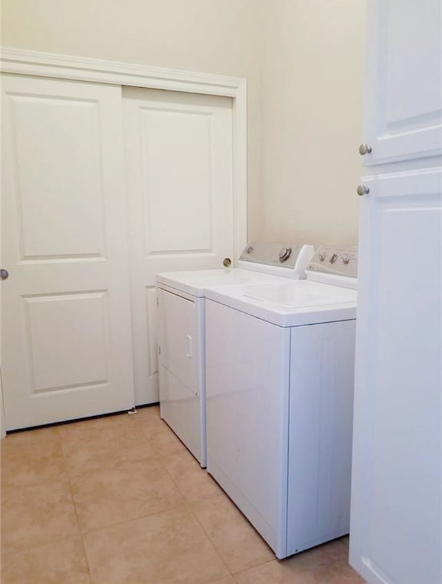 clothes washing area featuring light tile patterned floors and washer and clothes dryer