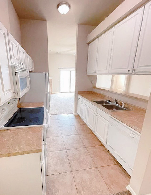 kitchen with light tile patterned floors, white appliances, white cabinetry, and sink