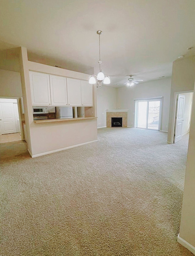 unfurnished living room featuring light carpet and ceiling fan with notable chandelier