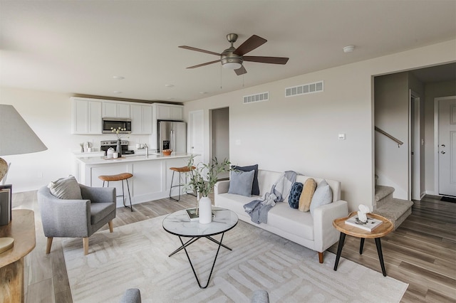 5130 Ella Ivy Ct, Van Meter, IA 50261 - living area featuring light wood-style flooring, a ceiling fan, and stairway