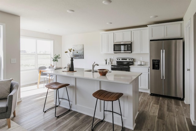 5130 Ella Ivy Ct, Van Meter, IA 50261 - kitchen with stainless steel appliances, a sink, wood finished floors, and a kitchen bar