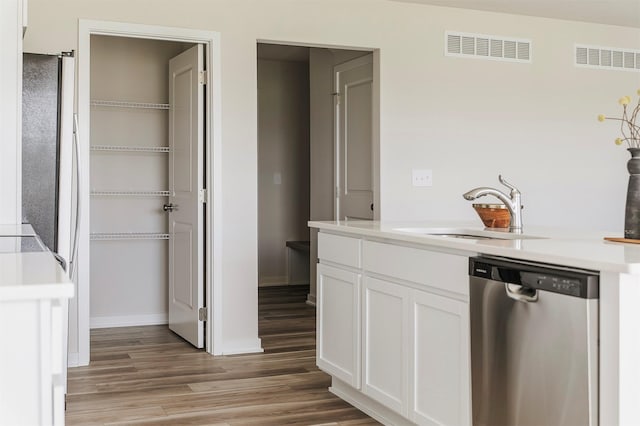 5130 Ella Ivy Ct, Van Meter, IA 50261 - kitchen featuring dishwasher, a sink, light wood-type flooring, white cabinetry, and light countertops