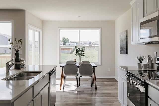 5130 Ella Ivy Ct, Van Meter, IA 50261 - kitchen with appliances with stainless steel finishes, a sink, wood finished floors, baseboards, and light countertops