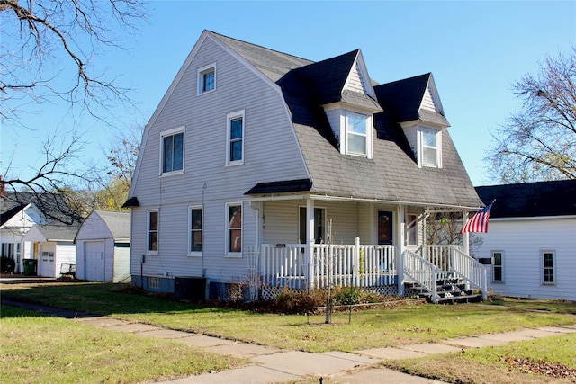 view of front of home featuring covered porch, a garage, an outbuilding, and a front yard