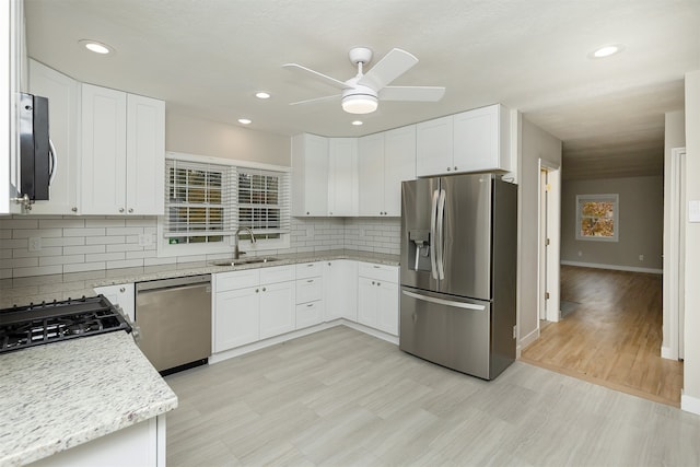 kitchen featuring white cabinets, sink, light hardwood / wood-style flooring, appliances with stainless steel finishes, and light stone counters