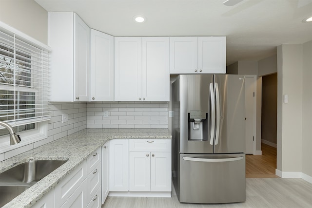 kitchen with tasteful backsplash, sink, light hardwood / wood-style flooring, white cabinets, and stainless steel fridge with ice dispenser