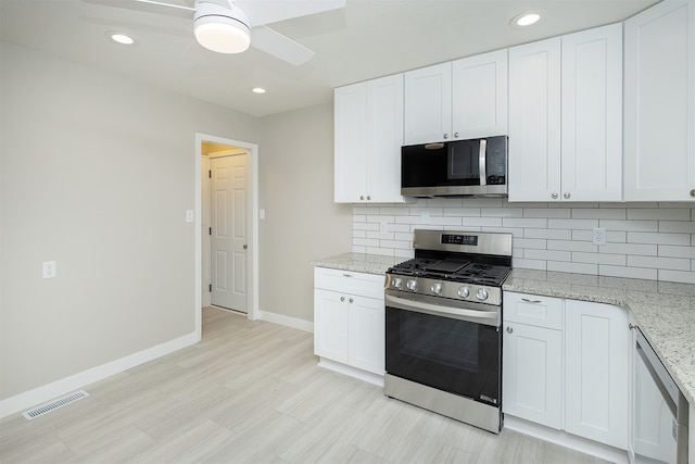 kitchen featuring white cabinets, decorative backsplash, light stone counters, and stainless steel appliances