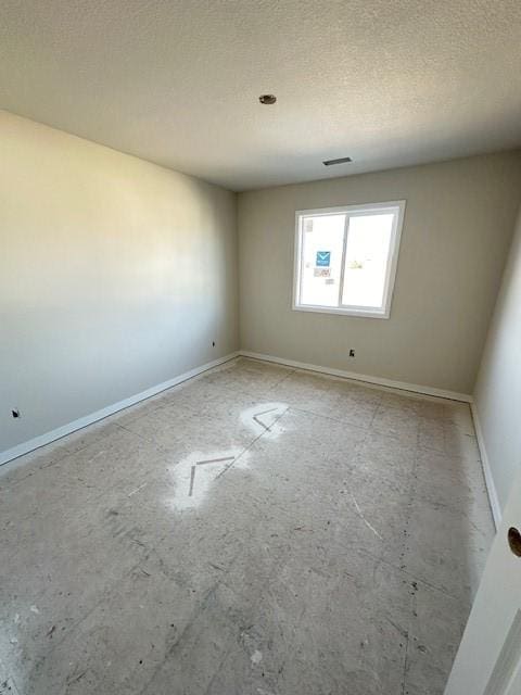 unfurnished room featuring visible vents, a textured ceiling, and baseboards