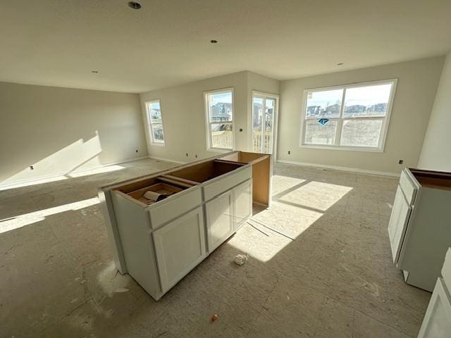 kitchen with open floor plan, baseboards, and white cabinets