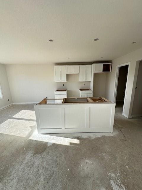 kitchen featuring baseboards, a kitchen island, and white cabinets