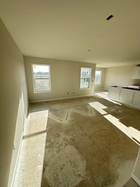 unfurnished room with a healthy amount of sunlight, visible vents, and baseboards