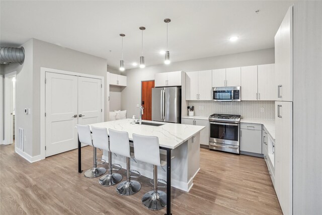 kitchen with appliances with stainless steel finishes, decorative light fixtures, white cabinetry, and sink