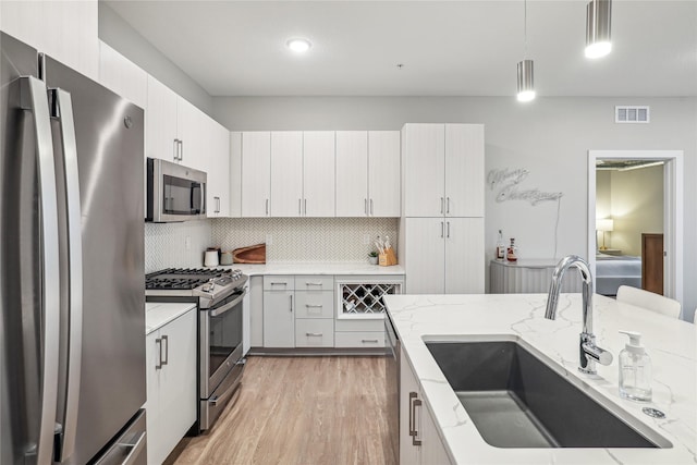 kitchen with visible vents, white cabinets, appliances with stainless steel finishes, pendant lighting, and a sink