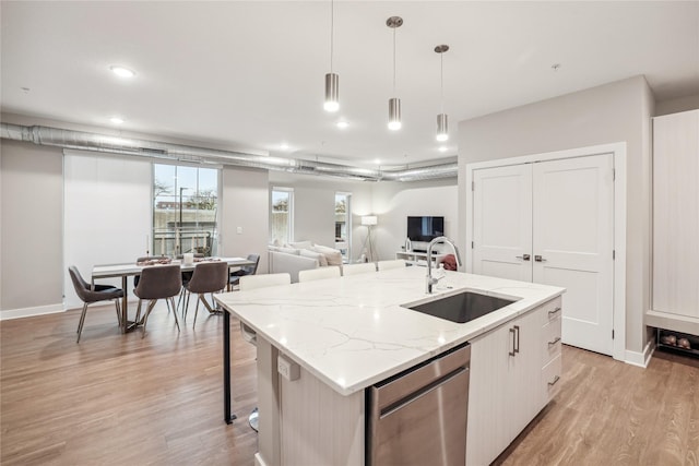 kitchen featuring dishwasher, open floor plan, a sink, and a center island with sink