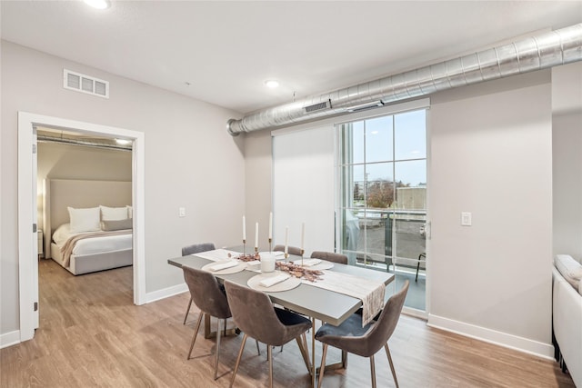 dining room featuring light wood-type flooring, visible vents, and baseboards