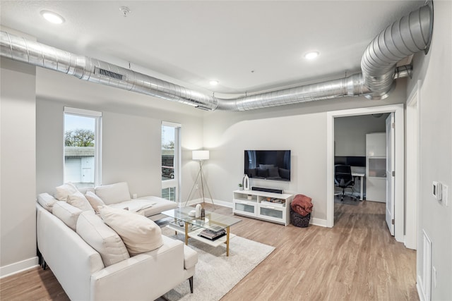 living area featuring baseboards, visible vents, and light wood-style floors