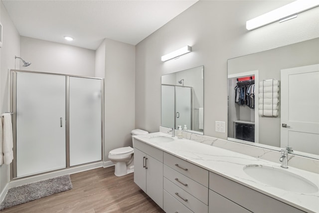 450 SW 7th St Unit 208, Des Moines, IA 50309 - bathroom featuring a shower stall, wood finished floors, double vanity, toilet, and a spacious closet