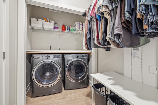 clothes washing area featuring laundry area, washing machine and dryer, and light wood-style flooring