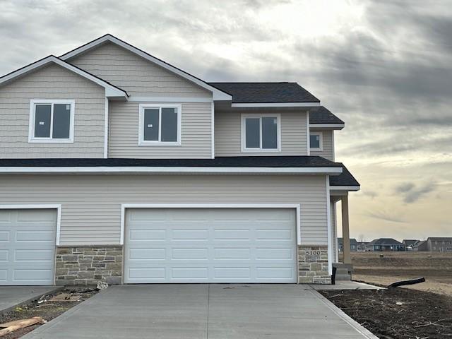 view of front facade featuring a garage, stone siding, and concrete driveway