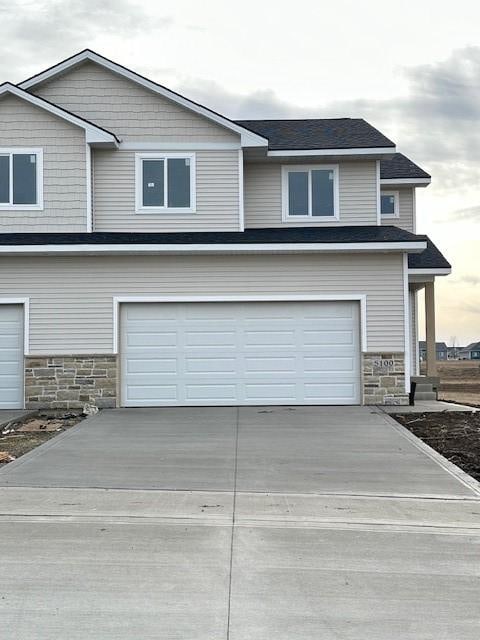 view of front of home featuring stone siding, concrete driveway, and an attached garage