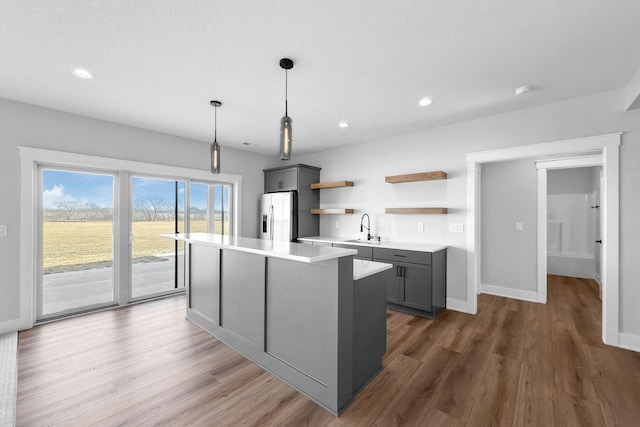 kitchen with gray cabinets, hardwood / wood-style floors, sink, hanging light fixtures, and stainless steel fridge with ice dispenser