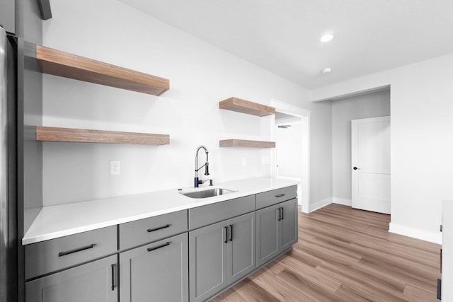 kitchen featuring gray cabinetry, sink, and light wood-type flooring