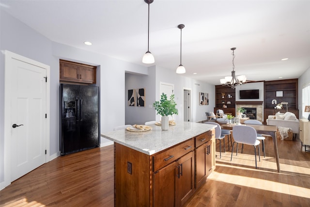 kitchen with black fridge, decorative light fixtures, open floor plan, a center island, and dark wood finished floors