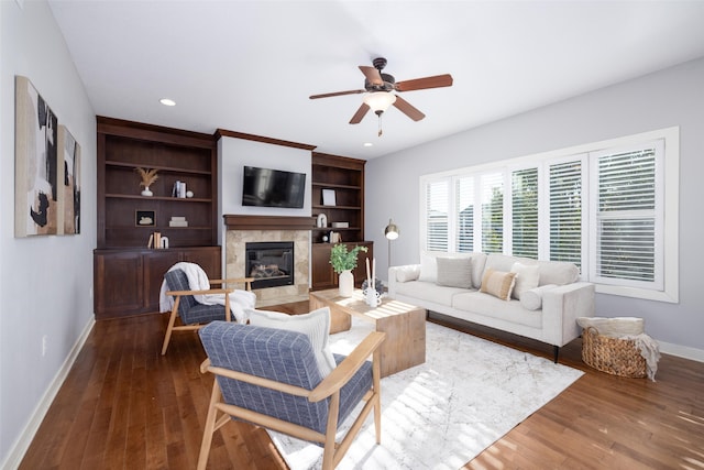 living room featuring wood finished floors, baseboards, a premium fireplace, recessed lighting, and ceiling fan