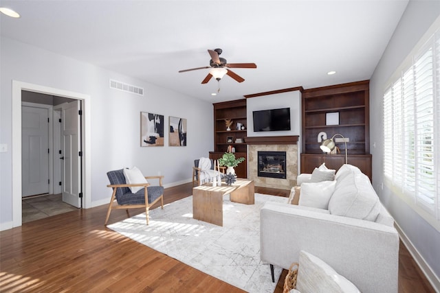 living area with wood finished floors, visible vents, a high end fireplace, and baseboards