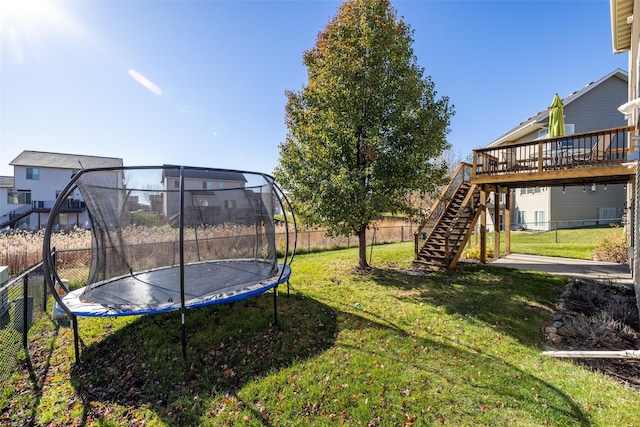 view of yard featuring a wooden deck, stairway, a trampoline, and a fenced backyard