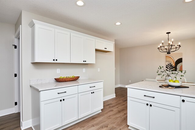 kitchen with hardwood / wood-style floors, white cabinets, decorative light fixtures, and a notable chandelier