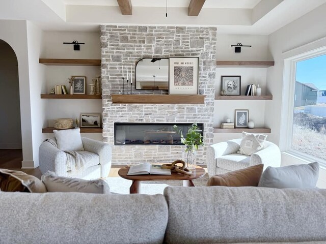 living room featuring built in features, hardwood / wood-style floors, and a stone fireplace