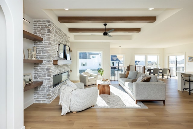 living room featuring hardwood / wood-style flooring, ceiling fan, beam ceiling, and a fireplace