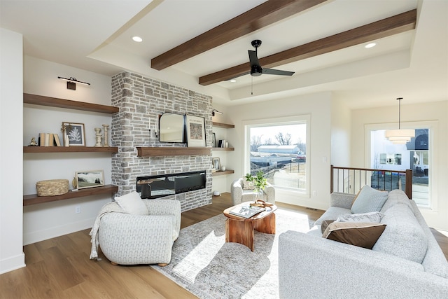 living area featuring a large fireplace, baseboards, wood finished floors, beamed ceiling, and recessed lighting