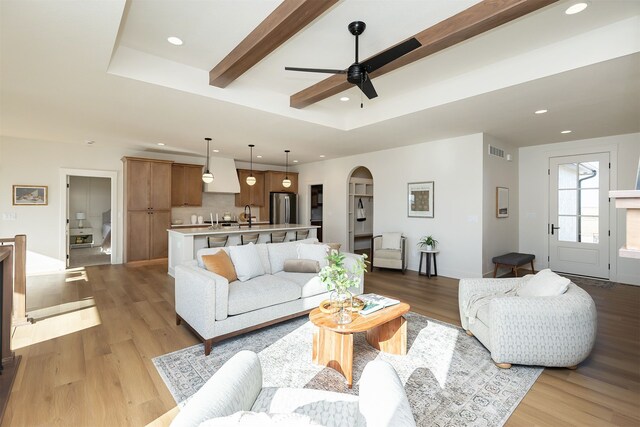 living room featuring light hardwood / wood-style floors, beam ceiling, and ceiling fan