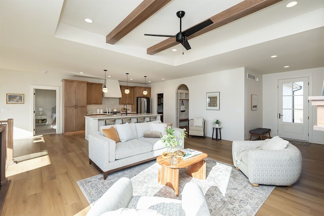 living room with arched walkways, visible vents, light wood-style flooring, and recessed lighting